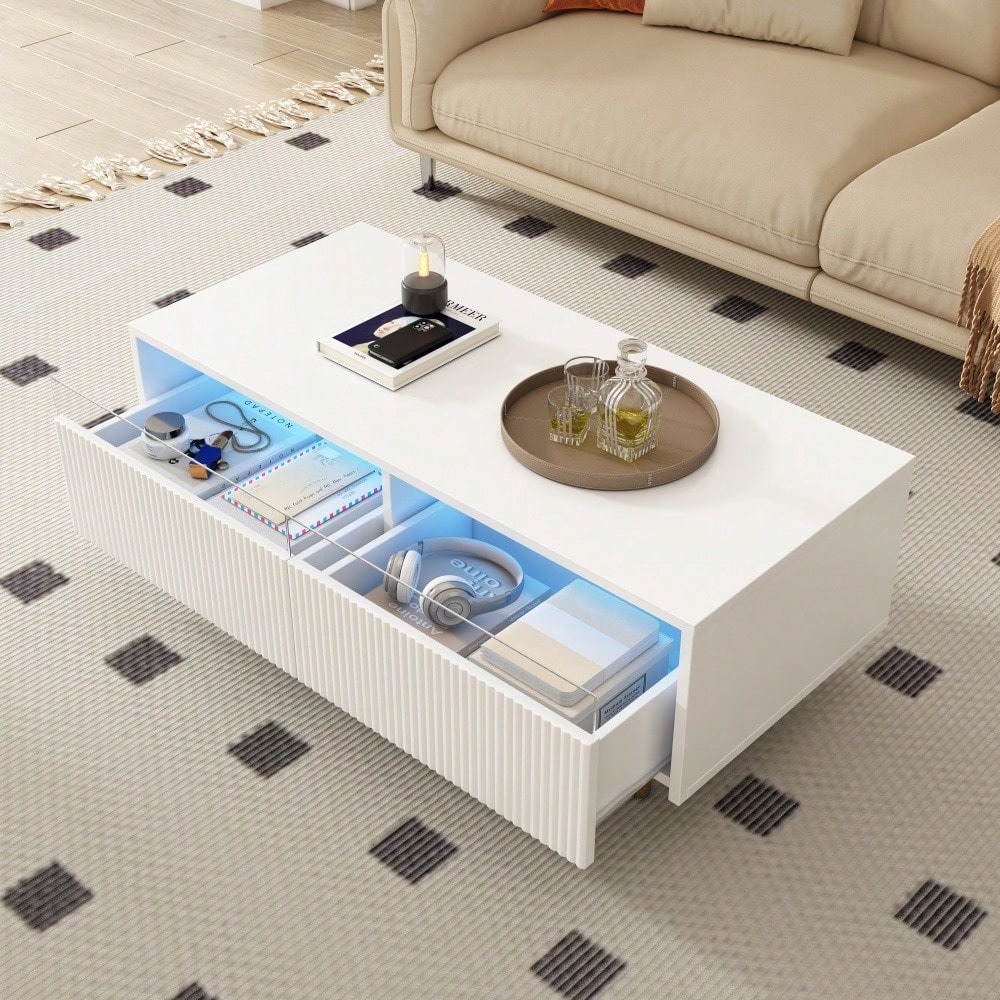 Dieser moderne LED-Couchtisch verfügt über eine gewellte Schubladenplatte, gold-weiße Beine, zwei Schubladen und einen farbwechselnden LED-Lichtstreifen. Ein passender TV-Schrank ist ebenfalls erhältl