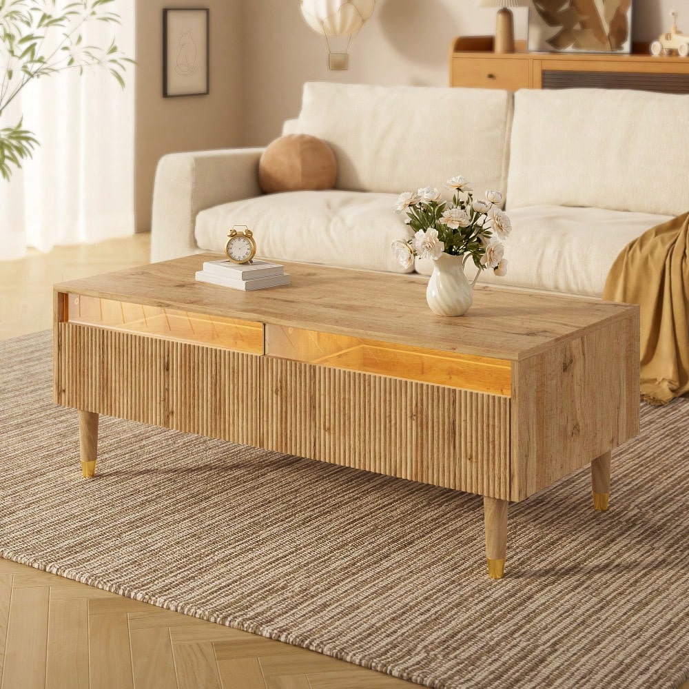 Dieser moderne LED-Couchtisch verfügt über eine gewellte Schubladenplatte, gold-holzfarbene Beine, zwei Schubladen und einen farbwechselnden LED-Lichtstreifen